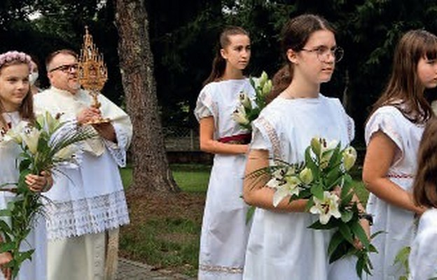 W procesji przy relikwiach świętej idą dziewczęta z białymi liliami