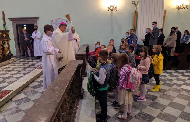 Biskup błogosławi tornistry najmłodszym uczniom. 