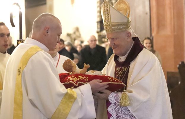 Bp Ignacy Dec na zakończenie uroczystej Pasterki w świdnickiej katedrze przenosi figurkę nowonarodzonego Dzieciątka Jezus do katedralnej szopki, podkreślając symbolikę narodzin Zbawiciela jako światła dla świata